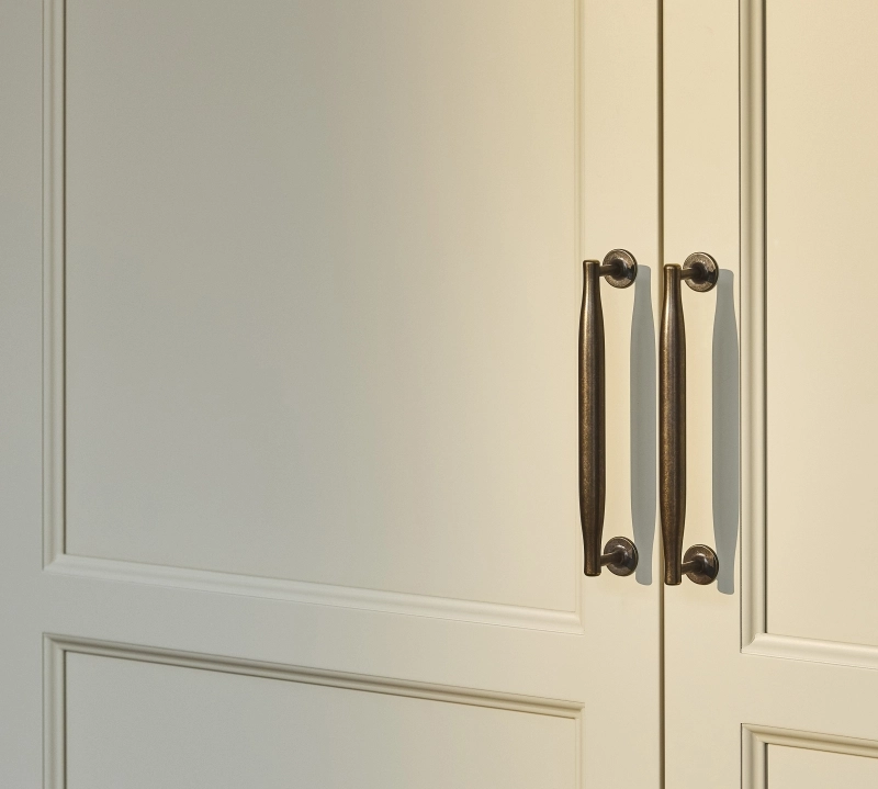 Close-up of a light brown wooden surface with distinct grain patterns. The texture shows subtle variations in color, ranging from warm amber to golden hues, emphasizing the natural characteristics of the wood.