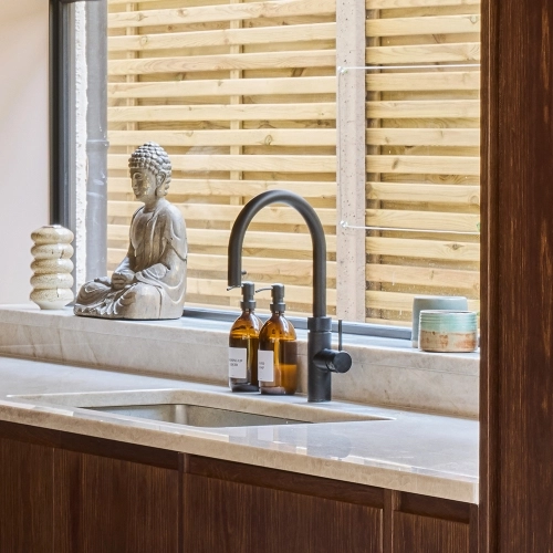 Modern kitchen with built-in double oven set in light blue cabinetry. Surrounding countertops and backsplash feature a white and gray marble pattern. A bowl filled with fruit sits on the left countertop.