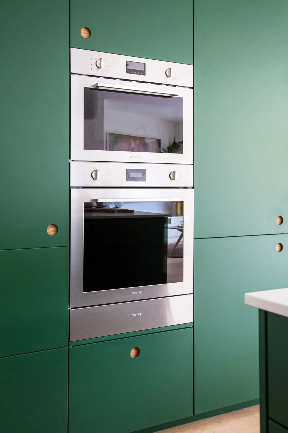 Discover the stunning Ascot kitchen, blending modern minimalist design with natural elements. Featuring Ladbroke doors in Wiveton Fern green, oak accents, and reeded glass cabinets.