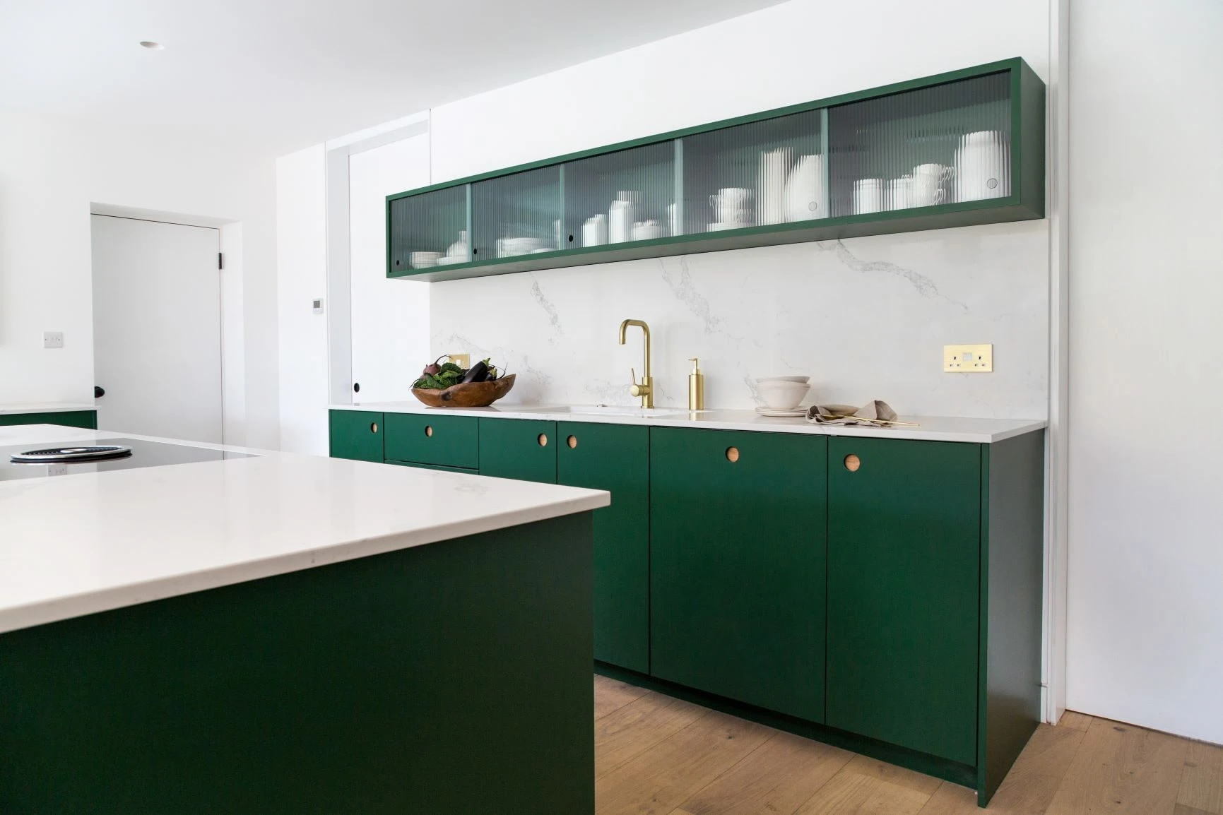 Wiveton Fern green Ladbroke doors stand out against neutral walls, creating a bold yet elegant statement in this bespoke kitchen. 