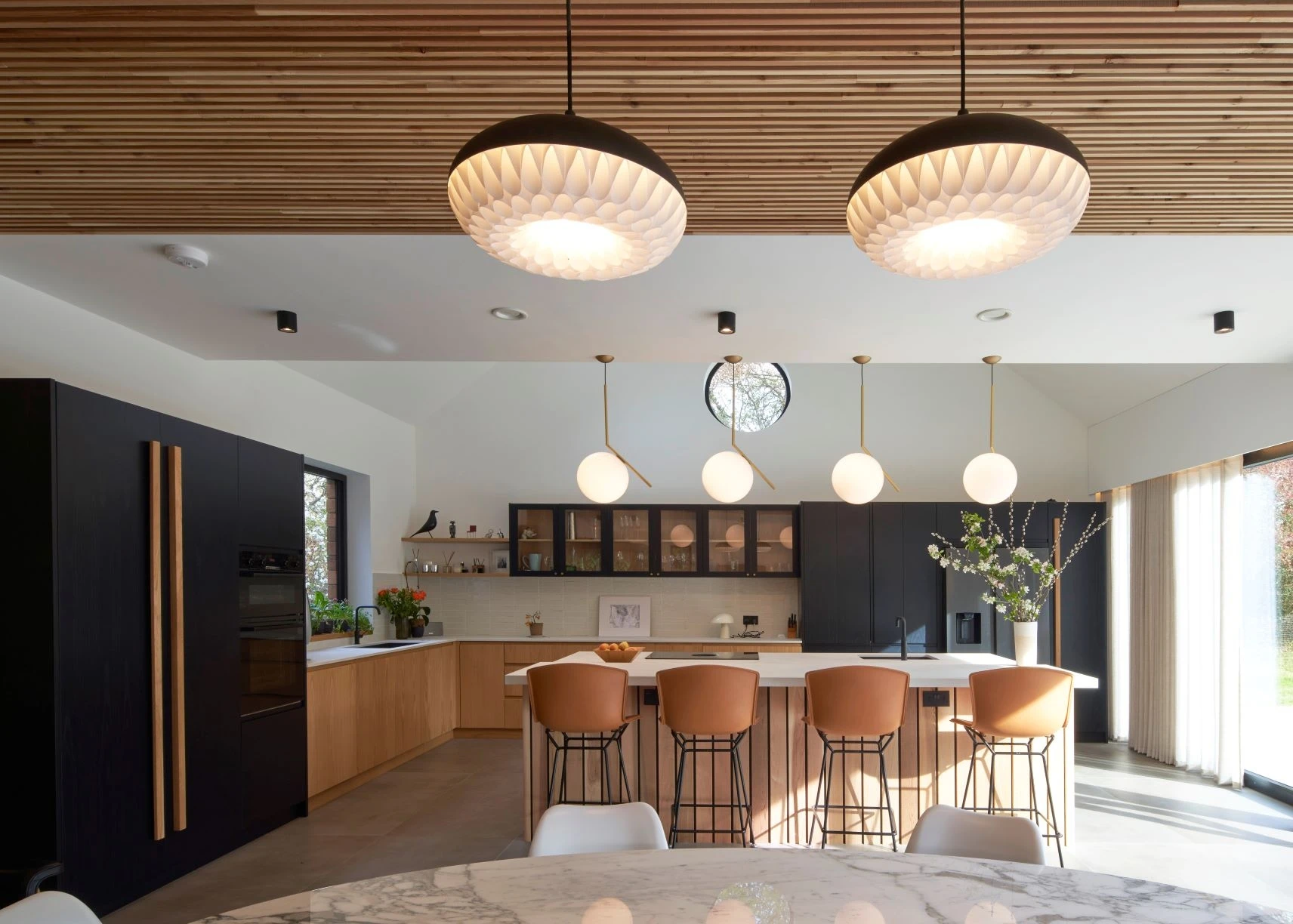 Modern oak J-Groove fronts in the Guildford kitchen add a touch of warmth and natural elegance to the sleek black cabinetry, creating a harmonious and inviting ambiance.