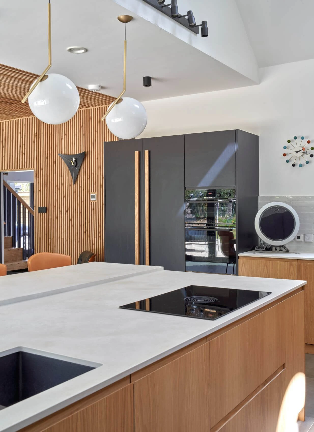 A sleek and sophisticated kitchen with dramatic black cabinetry, accented by exposed oak J-Groove fronts, exuding a modern and minimalist aesthetic.