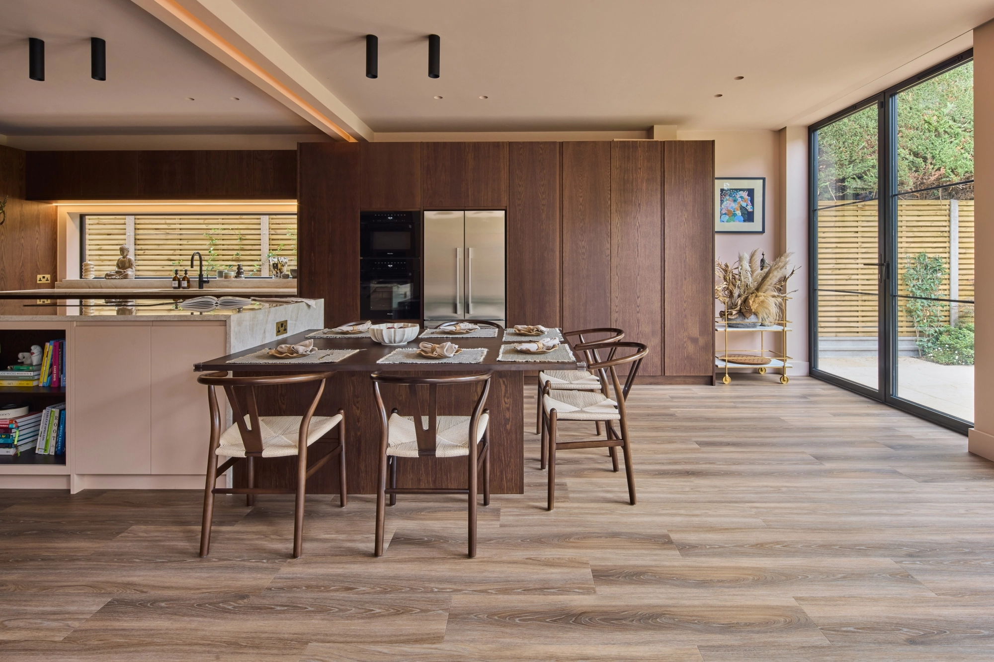 A wooden cabinet with glass doors displaying ceramic dishes, bowls, and a jug. Below is a light blue drawer set with a marbled countertop. Warm lighting highlights the textures and tones of the ceramics and wood