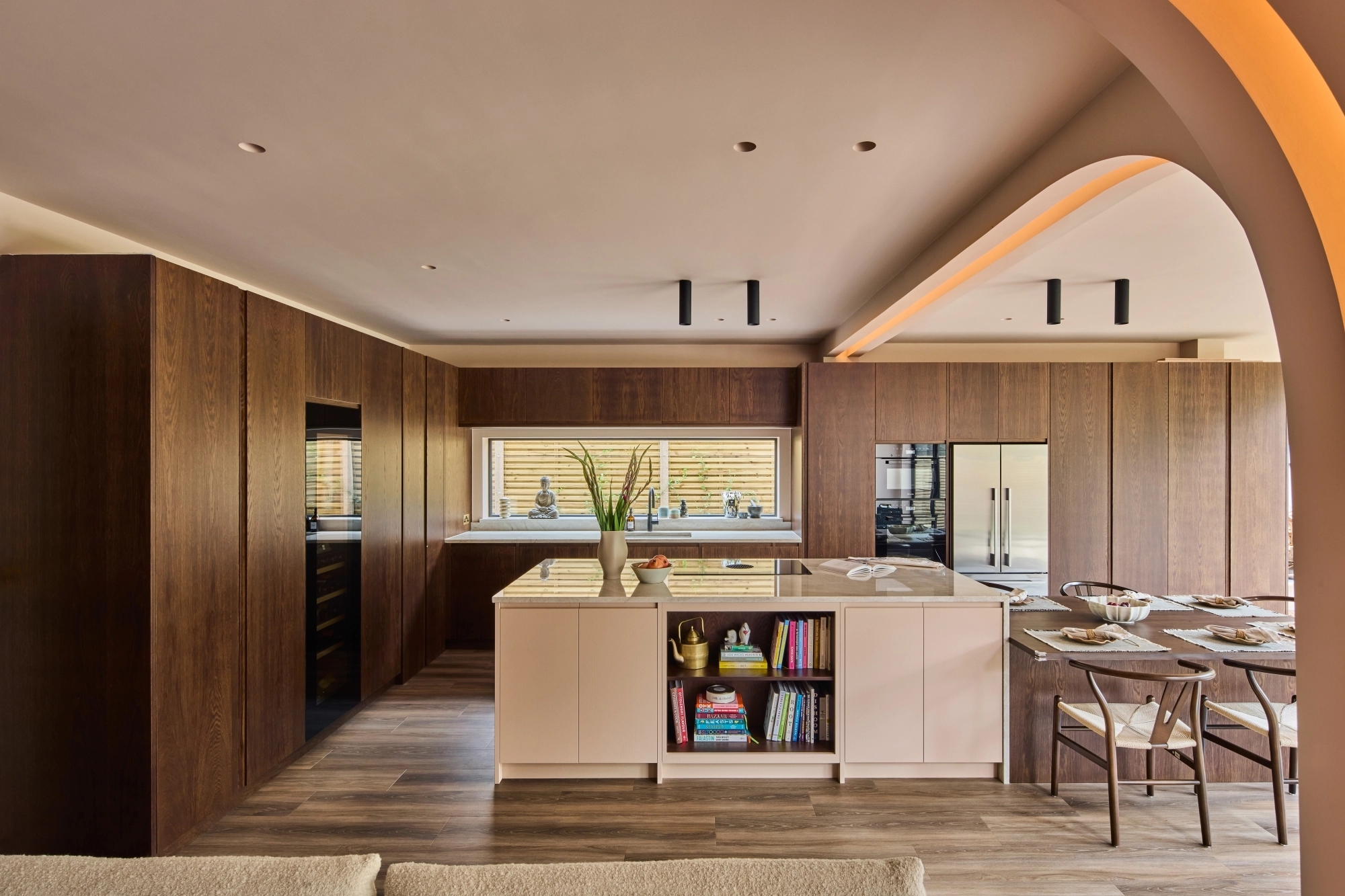 A wooden cabinet with glass doors displaying ceramic dishes, bowls, and a jug. Below is a light blue drawer set with a marbled countertop. Warm lighting highlights the textures and tones of the ceramics and wood