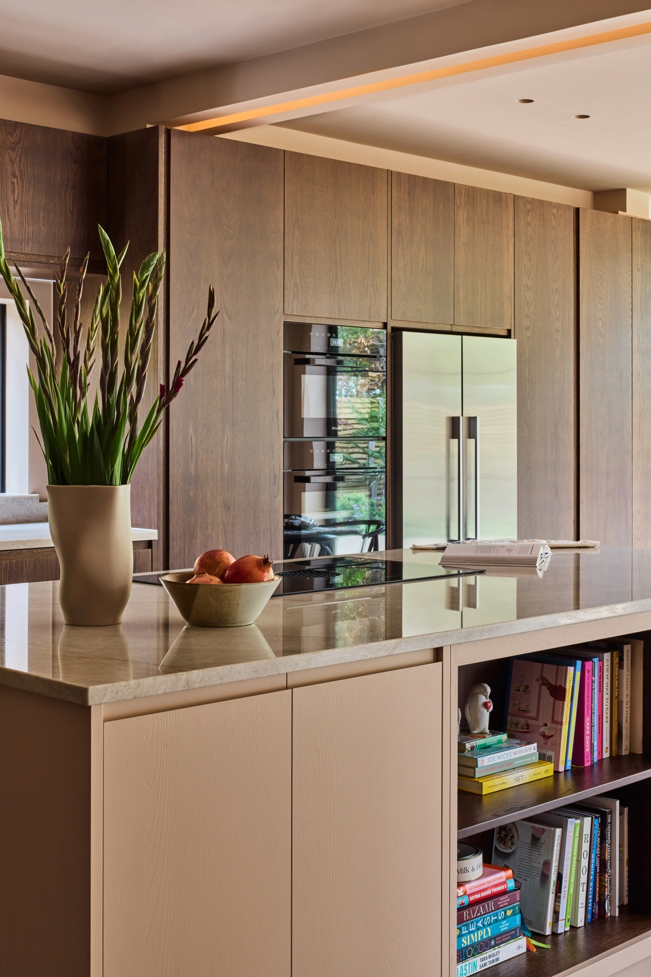 Close-up of a wooden cabinet with two open doors featuring round, textured metal knobs. Inside, there are neatly stacked plates with gold rims. The cabinet is set on a marbled surface