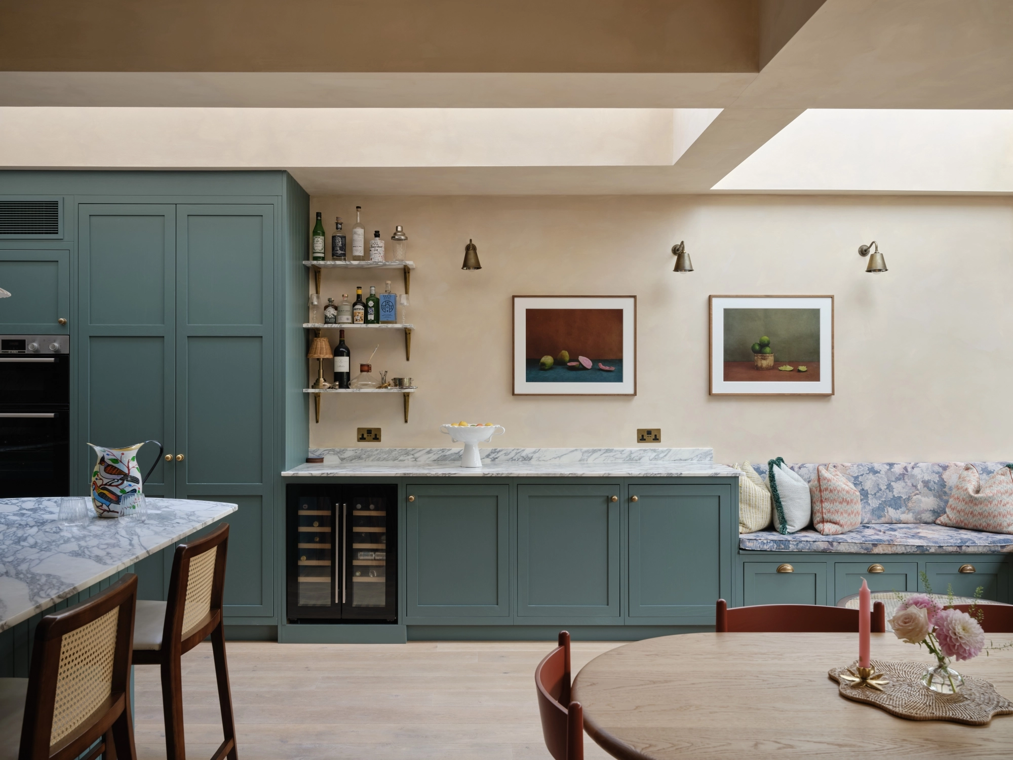 A wooden cabinet with glass doors displaying ceramic dishes, bowls, and a jug. Below is a light blue drawer set with a marbled countertop. Warm lighting highlights the textures and tones of the ceramics and wood