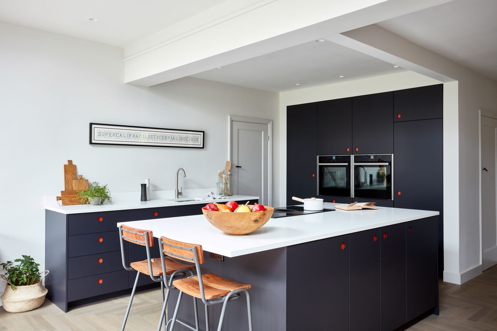 dark blue ladbroke handleless kitchen with red backings