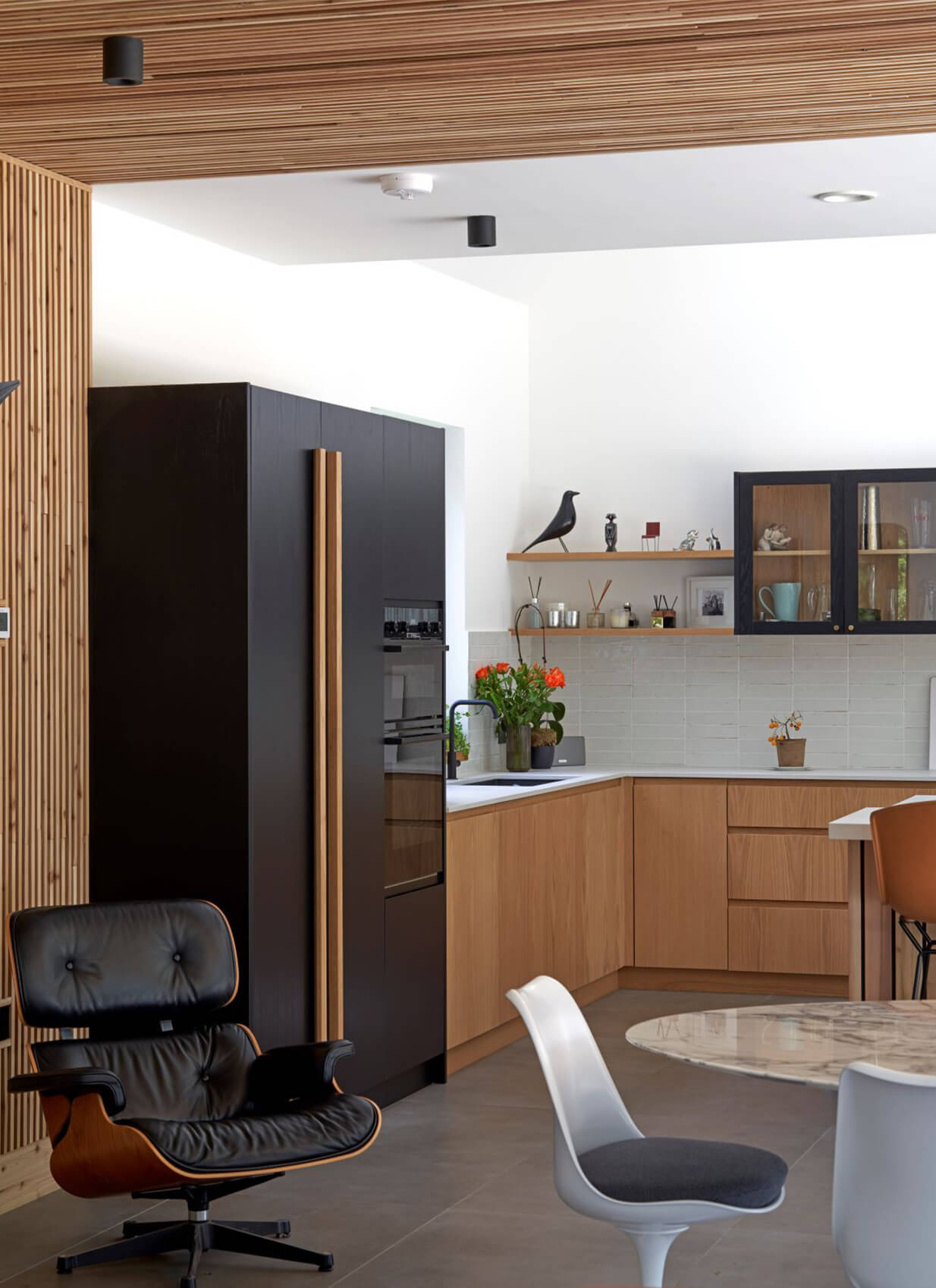 Large black and oak kitchen with glazed wall cabinet with j-groove doors and an island with a v-groove finish
