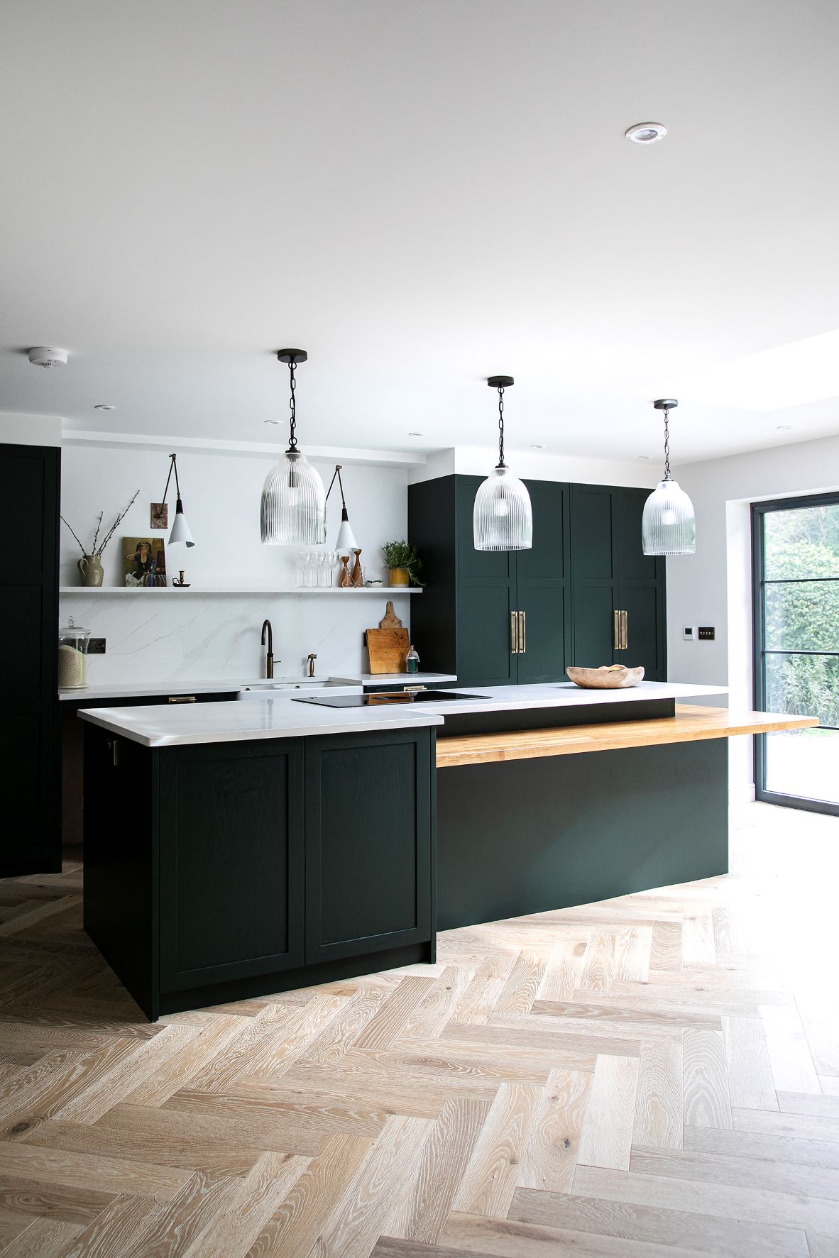 black shaker style kitchen with integrated oven and white worktops and a central island to match